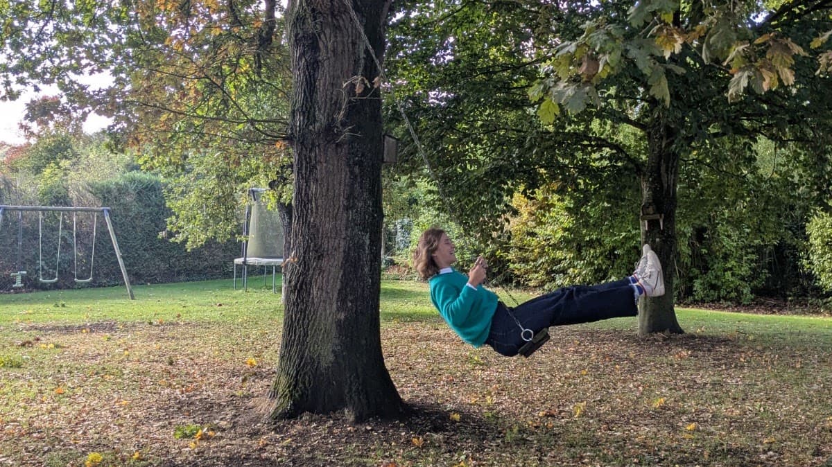 Personne souriante sur une balançoire accrochée à un arbre